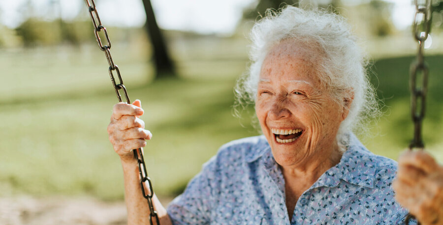 Cheerful senior woman on a swing at a playground